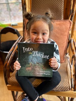 Little girl sitting with Into the Thicket