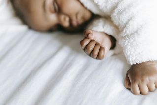 Close-up of a serene baby sleeping peacefully with a soft focus on their gentle hands.