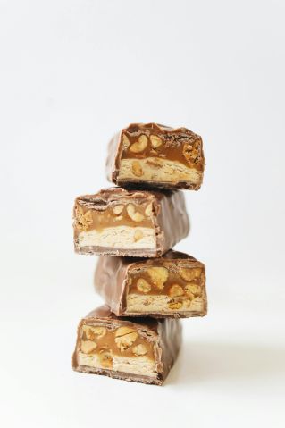 Close-up of stacked chocolate bars with nougat and peanut filling.