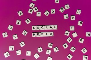 Alphabet tiles forming 'Social Media' on a vibrant pink background, perfect for digital marketing themes.