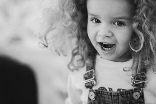 Playful black and white portrait of a happy child laughing, capturing pure innocence and joy.