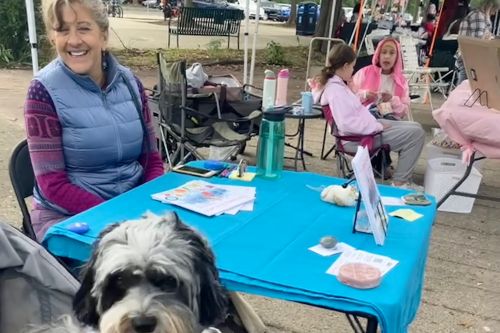 Gail at Rumble of the Bumble table, dog visitor in foreground