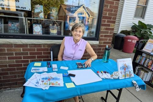 Gail Kuhnlein at her author table with book, How Happy Is a Lark? Out front of Adventure, Ink