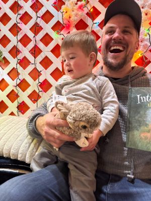 Little boy on father's lap with rabbit stuffie and Into the Thicket beside them