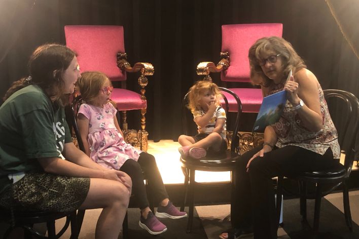 Gail reading to a mother and her two daughters at Coreander's