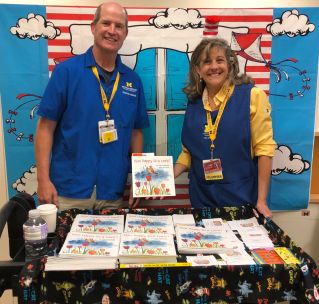 Tim and Gail with book cart standing in front of Cat in the Hat backdrop