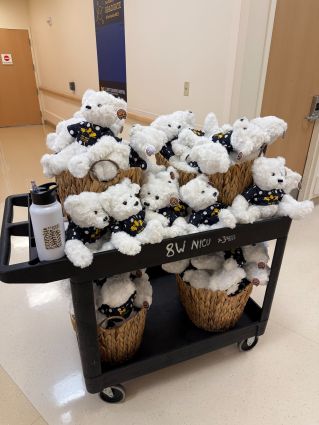 a cart carrying baskets full of white teddy bears wearing Tshirts for the Mott Golf Classic for the UM NICU babies