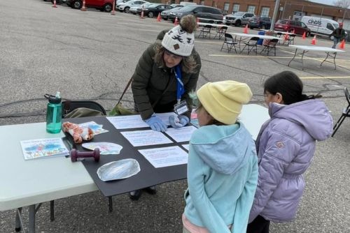 Gail at her table outside, talking with two children