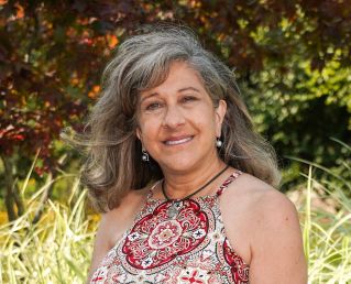 head and shoulders photo of Gail Kuhnlein in backyard with trees and grasses in background